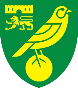 Badge of Norwich City: a green shield with yellow emblems. A bird (canary) on top of a ball as the main image, and a castle above a lion passant guardant in the top left quarter.