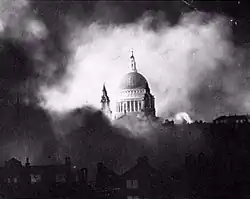 Black and White photograph of the dome of St Paul's, starkly lit, appearing through billowing clouds of smoke