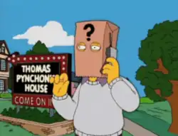 Cartoon frame showing a man with a paper bag over his head talking into a mobile phone. The bag has a large question mark printed on it and the man stands in front of a large illuminated sign in block letters which says 'THOMAS PYNCHON'S HOUSE – COME ON IN'